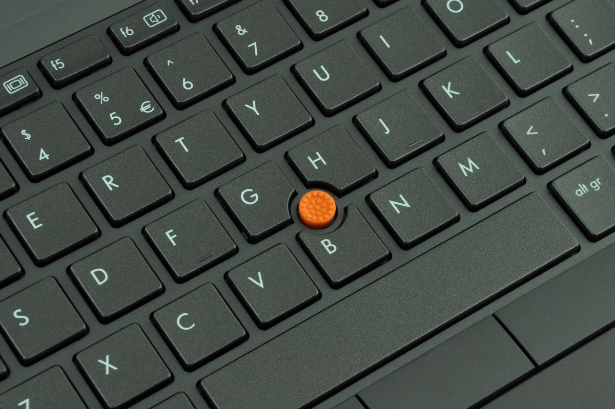 Close-up of a laptop keyboard with an orange pointing stick between the G, H, and B keys in the center of the board.