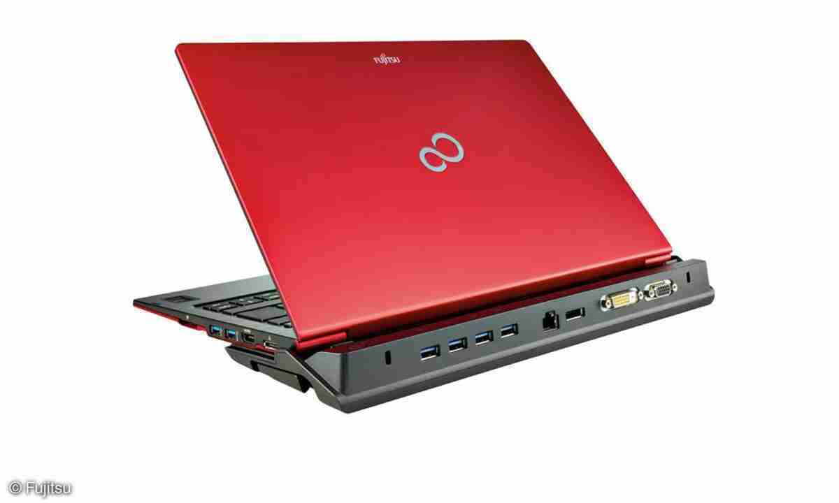 Fujitsu LifeBook U772_0306_04 - lab-kuzniewski.pl - Testy laptopów, recenzje i porównania Red Fujitsu laptop connected to a docking station with multiple USB and video ports visible on the dock.