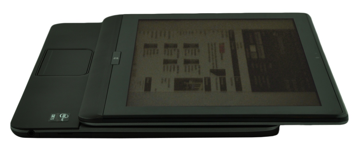 Side view of a black convertible tablet with docked keyboard and a large touchscreen display, viewed from the left/above edge of the screen.