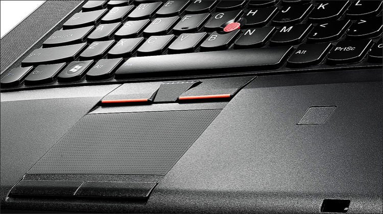 Close-up of a laptop keyboard and touchpad, featuring a red TrackPoint between the keys.