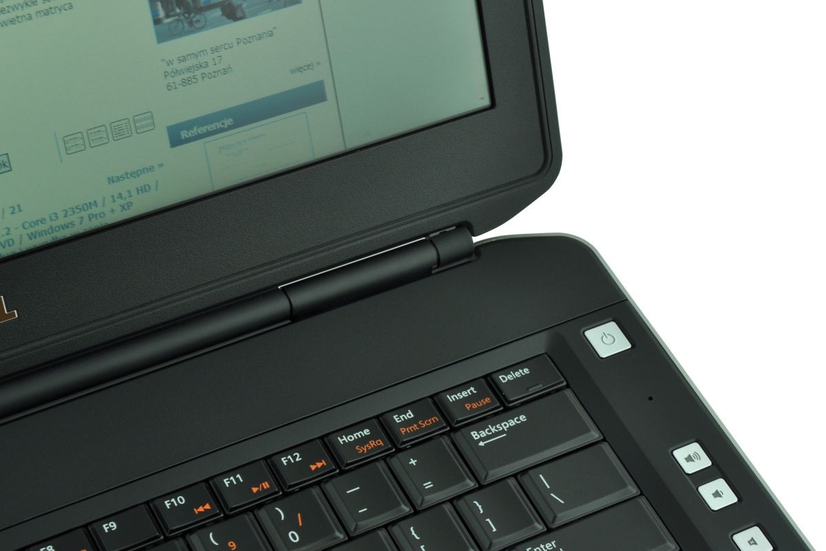 dell-latitude-e5430-5161_125275 - lab-kuzniewski.pl - Testy laptopów, recenzje i porównania Close-up of a dark laptop keyboard and hinge area, with a visible screen in the background and a power button near the top-right corner on the palm rest.