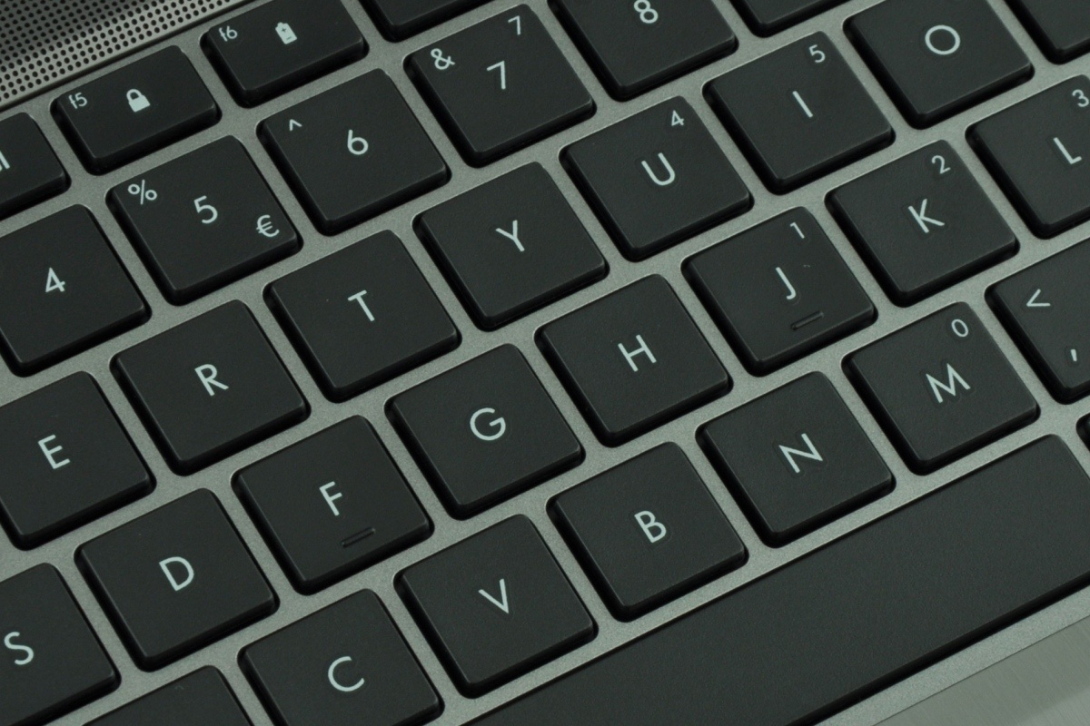 Close-up of a dark gray laptop keyboard with white letters visible on each key.
