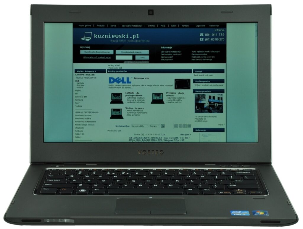 Open black Dell Vostro laptop displaying a blue website homepage on the screen (kuzniewski.pl).