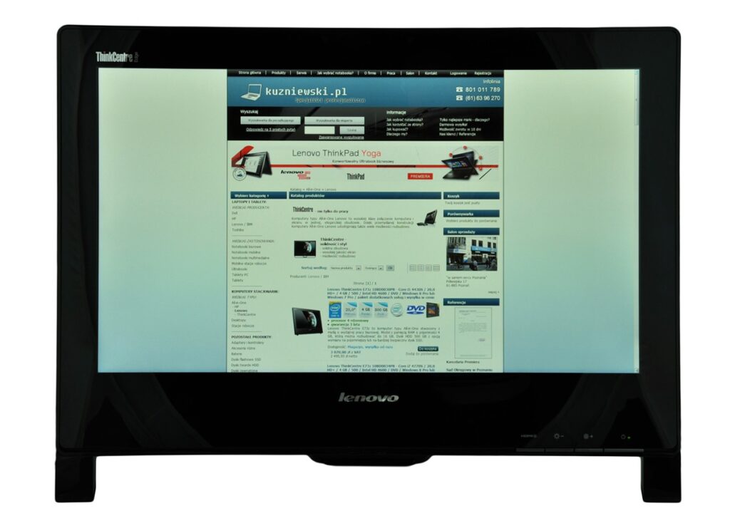 Monitor displaying a Lenovo all-in-one screen with a webpage about a Polish site, ThinkCentre branding visible on bezel