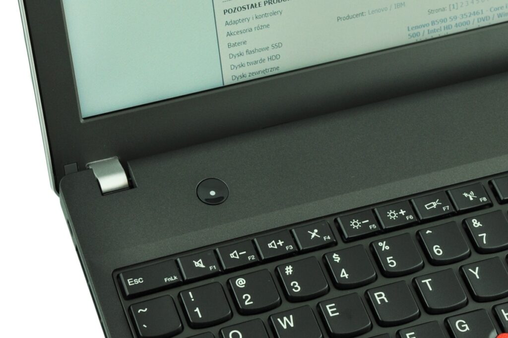 Close-up of a laptop keyboard near the hinge, showing the round power button and row of function keys.