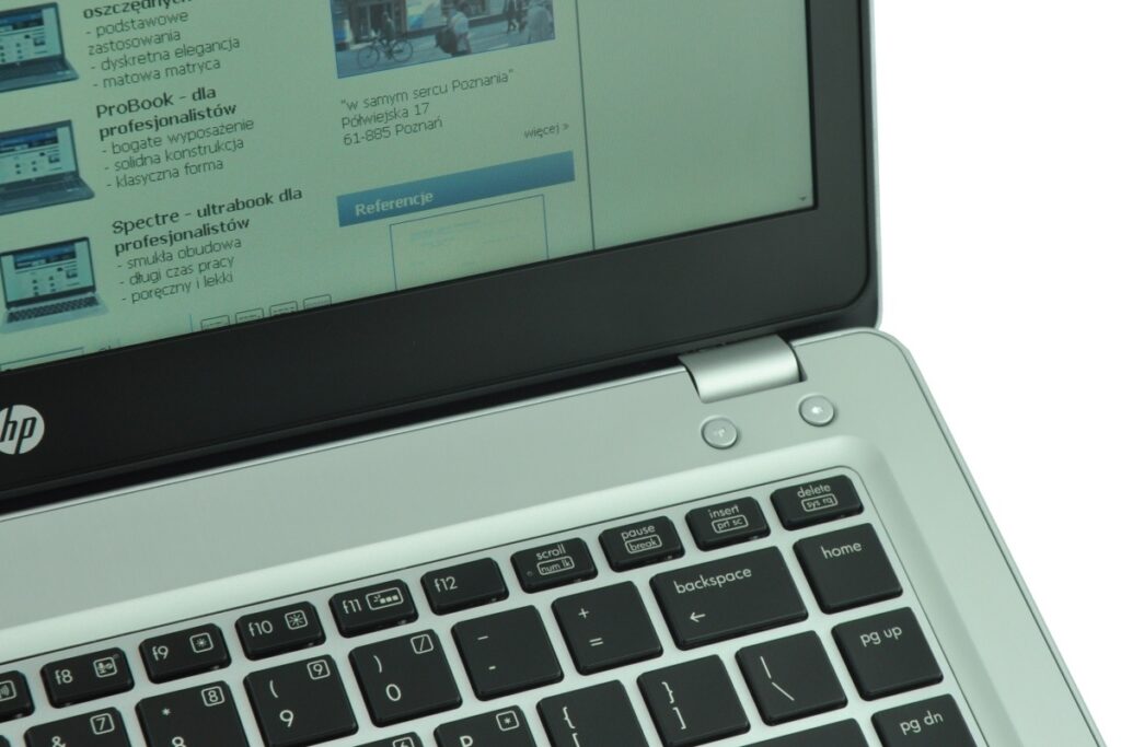 Close-up of an HP laptop showing a Polish website on the screen and a partial keyboard visible.