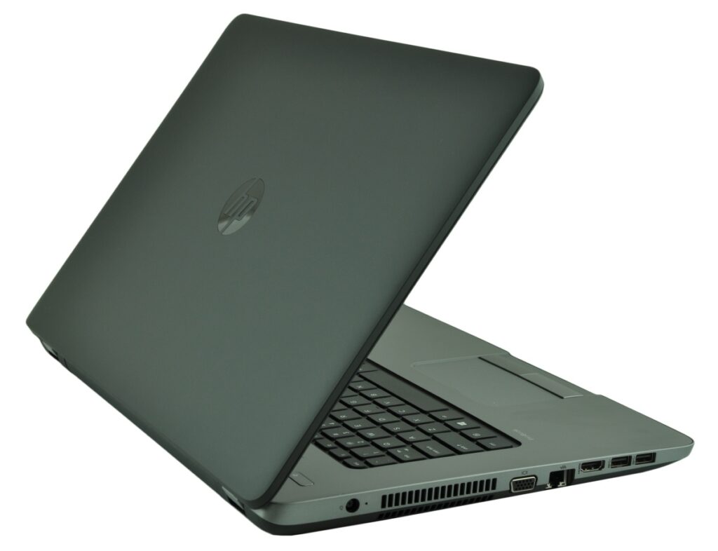 Open gray HP laptop photographed from a side angle showing keyboard and ports with screen slightly angled back.
