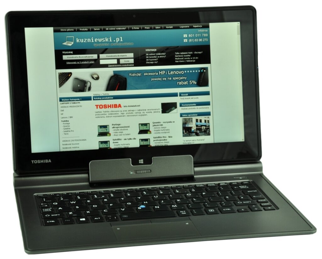 Open Toshiba laptop displaying a Polish tech website with a blue header and grid content on screen.