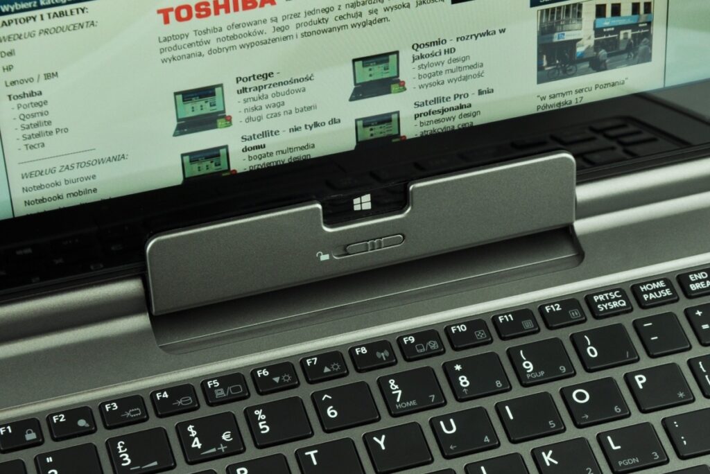 Close-up of a laptop with a Toshiba advertisement displayed on the screen and a silver docking area above the keyboard.