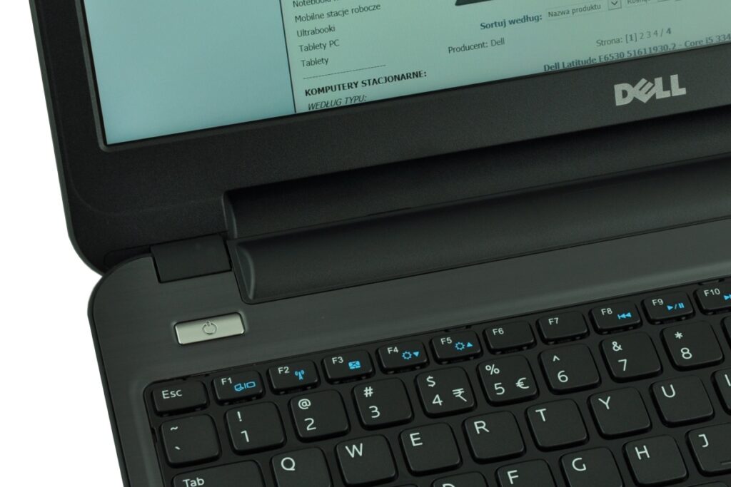 Close-up of a Dell laptop keyboard with a power button on the left and the screen showing a greenish document.