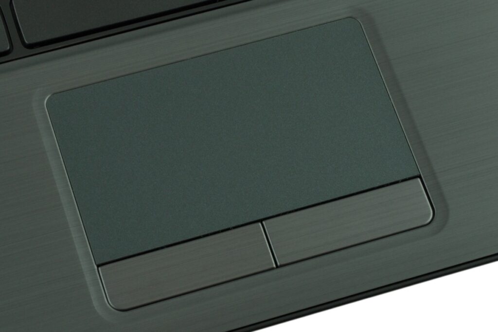 Close-up of a grey laptop touchpad with two rectangular buttons beneath it, on a brushed-metal surface.