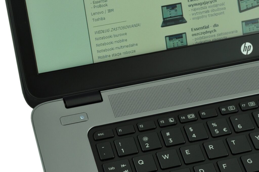 Close-up of an HP laptop showing the gray chassis, keyboard, and speaker grille with a document on the screen.