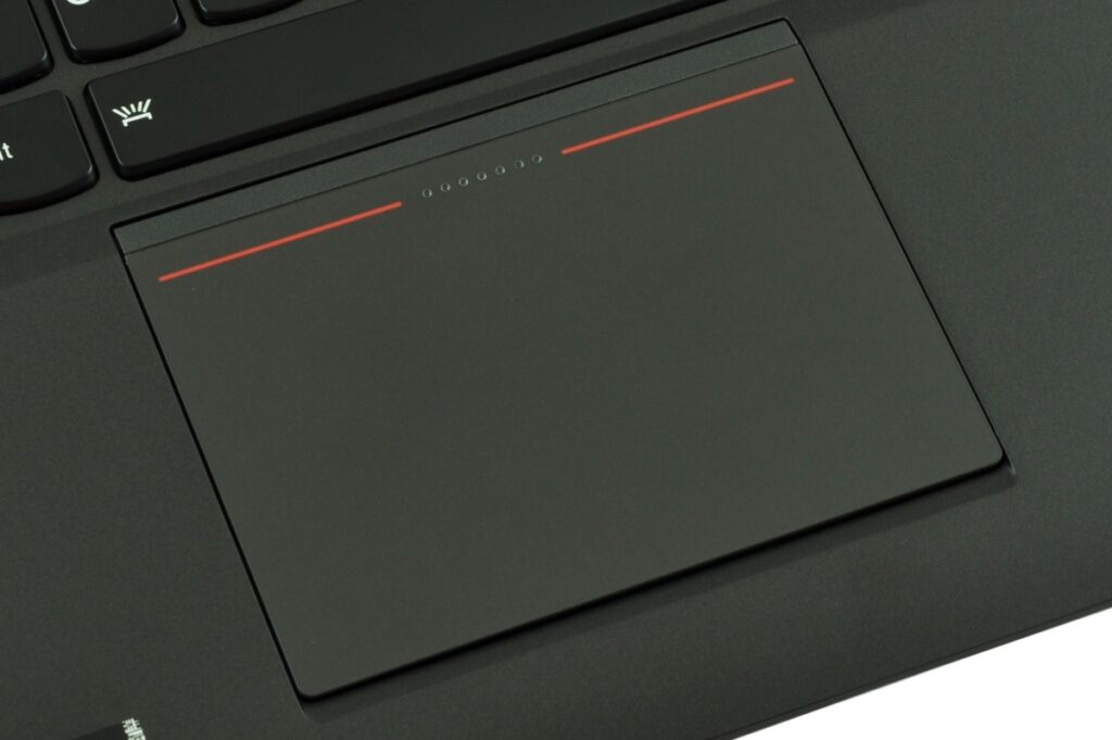 Close-up of a black laptop touchpad with red accent lines above it and a keyboard edge visible to the top left (informative: touchpad area).