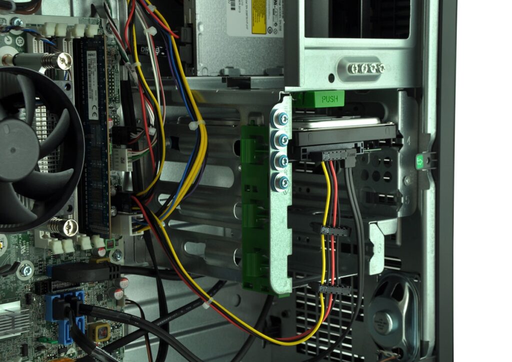 Inside a computer case showing a motherboard, fans, and a drive cage with colorful power and data cables connected to components.