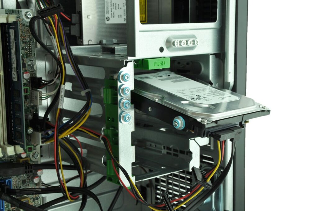 Inside a computer: hard drive mounted in a drive bay with cables and circuit boards visible.