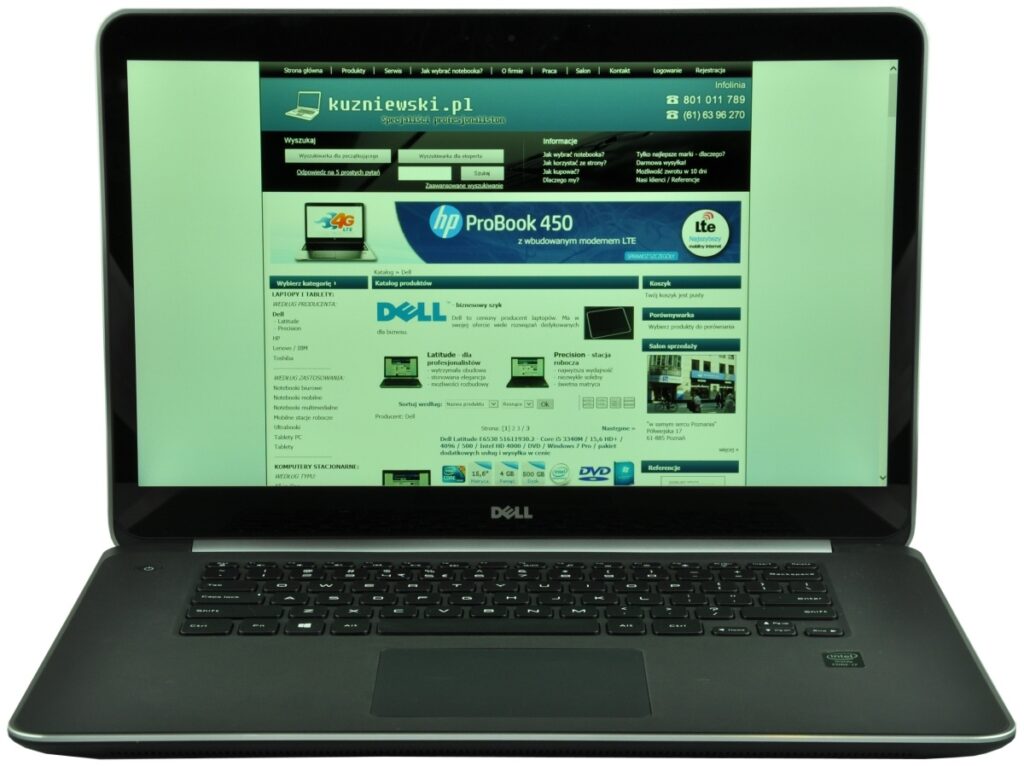 Open Dell laptop with the screen displaying a Polish tech website (kuzniewski.pl) in a blue-green header and navigation, Dell logo visible on the laptop bezel.