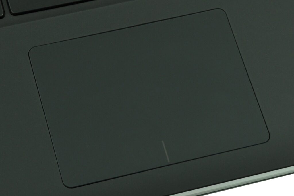 Close-up of a dark laptop touchpad with a small light vertical line near the bottom center.