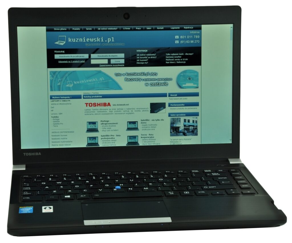 Open Toshiba laptop displaying a Polish website kuzniowski.pl on the screen, with a blue navigation bar and content panels.