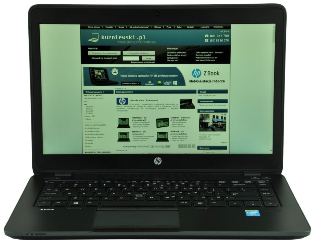 HP laptop open to a Polish tech site kuzniewski.pl displayed on screen, with a dark keyboard on a white background (greenish tint).