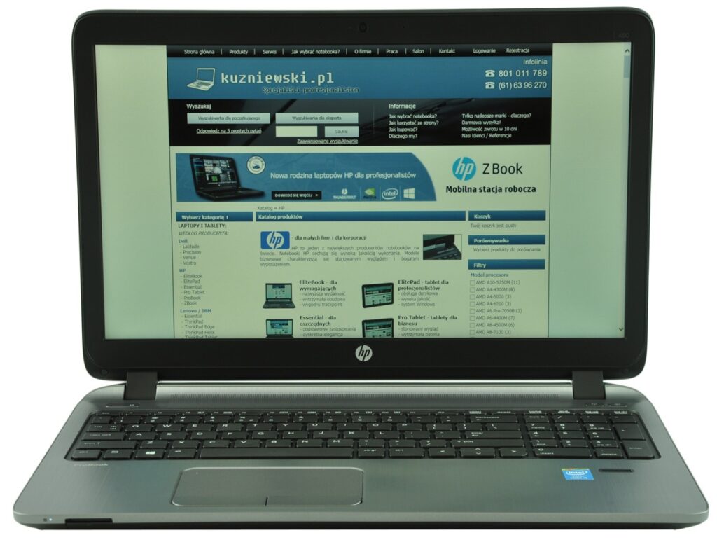 HP laptop open and displaying a Polish tech website on the screen, blue header with logo and navigation
