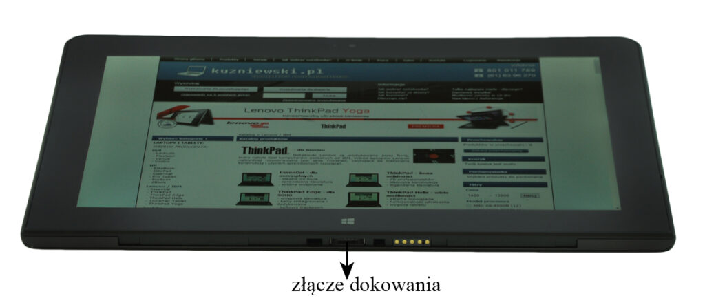 Bottom view of a tablet/2-in-1 with a visible docking connector (gold pins) at the base and a web page displayed on the screen.