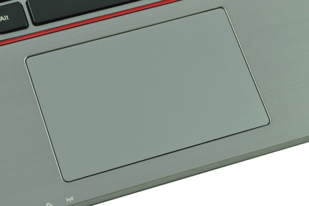 Close-up of a large gray laptop touchpad on a silver chassis with a slim border and red accent line above it.