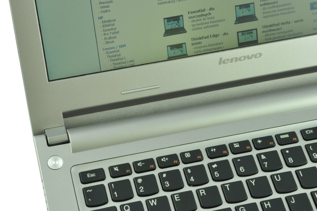 lenovo-m30-70-59-428988_130067 - lab-kuzniewski.pl - Testy laptopów, recenzje i porównania Close-up of a silver Lenovo laptop opened at an angle, showing the keyboard and a screen with text.
