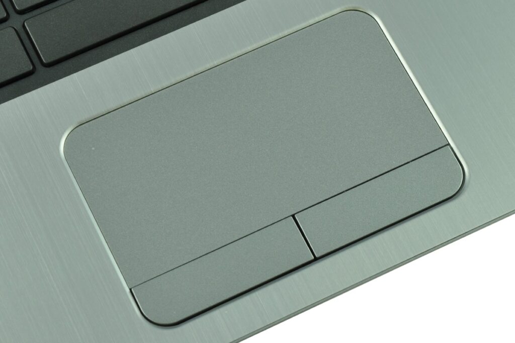 Close-up of a silver laptop touchpad with two small click buttons on a brushed metal surface.