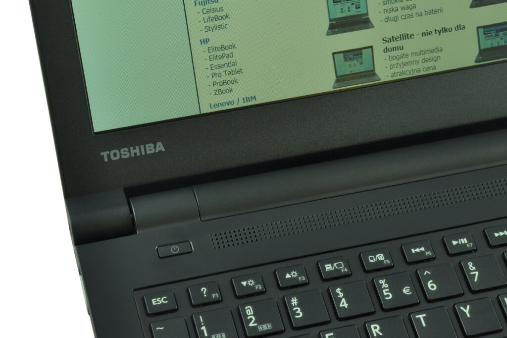 Toshiba laptop open on a desk, showing a keyboard and a green-tinted webpage on the screen.