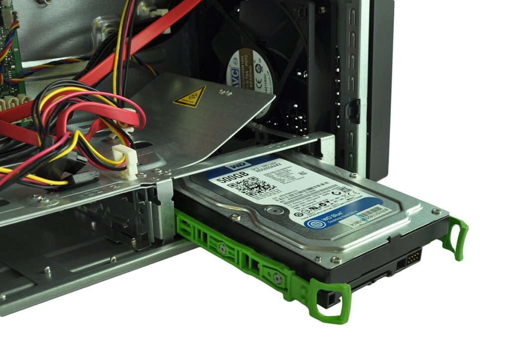 Internal view of a computer/server with a 500GB hard drive partially slid out of the drive bay, surrounded by colorful power/data cables and a green sled piece.