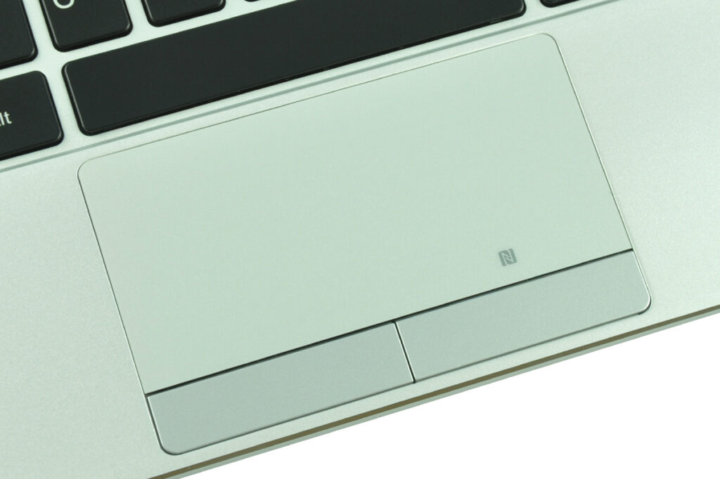 Close-up of a laptop touchpad with two physical clicks and an NFC logo on a light-colored palm rest area.