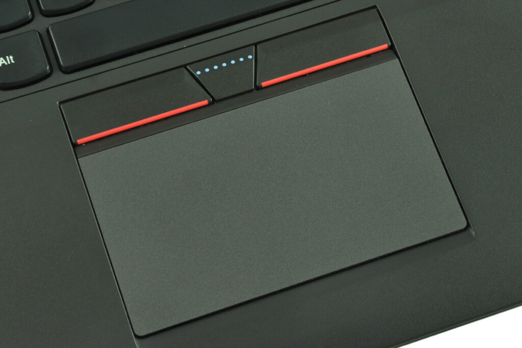 laptop-lenovo-thinkpad-t550-6 - lab-kuzniewski.pl - Testy laptopów, recenzje i porównania Close-up of a dark laptop touchpad with red-edged left and right buttons and a center button showing blue indicator dots.