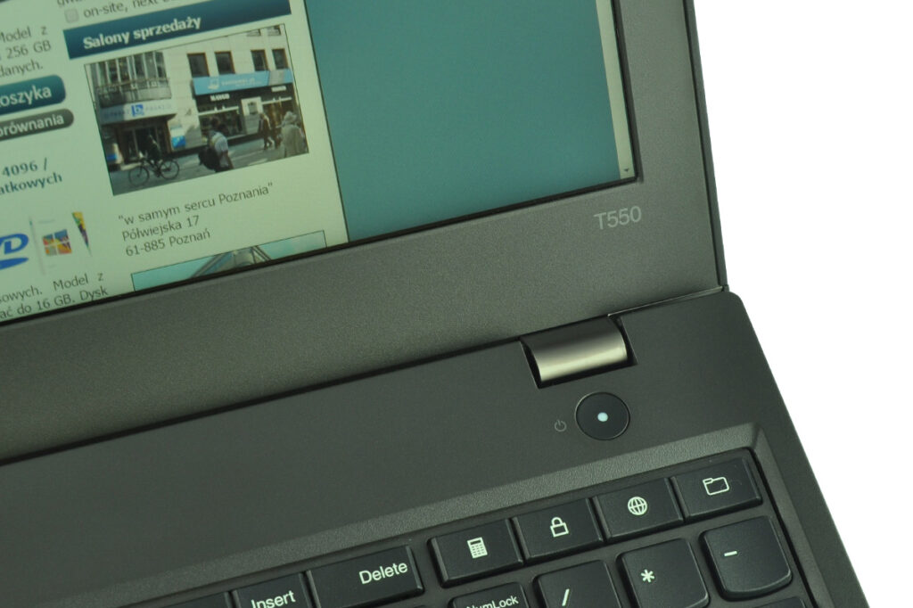 laptop-lenovo-thinkpad-t550-8 - lab-kuzniewski.pl - Testy laptopów, recenzje i porównania Close-up of a dark laptop keyboard and hinge with a screen showing a webpage; model badge reads T550 on the chassis.