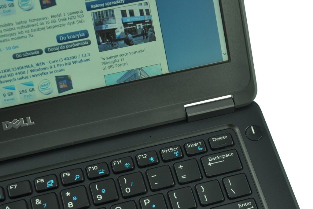 dell-latitude-e5250-ca01_131702 - lab-kuzniewski.pl - Testy laptopów, recenzje i porównania Close-up of a Dell laptop open to a webpage, showing the Dell logo on the chassis and a black keyboard with a blue-toned screen.