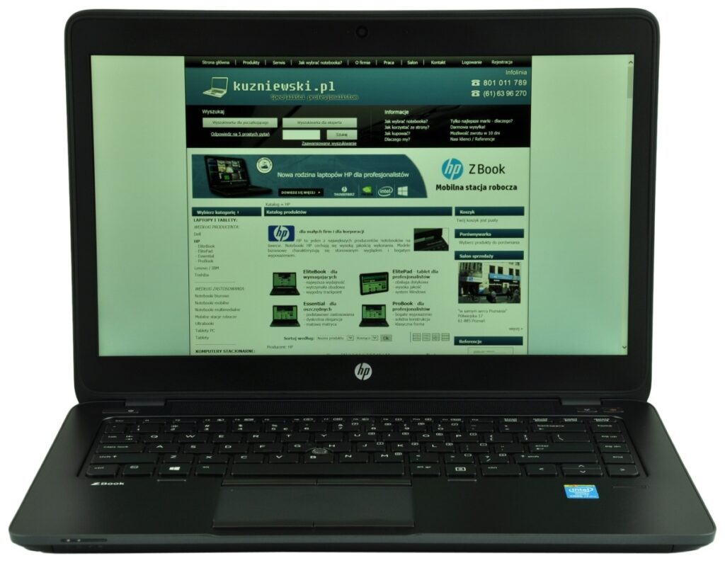 hp-zbook-14-g2-j8z75ea-c_130725 - lab-kuzniewski.pl - Testy laptopów, recenzje i porównania Open HP laptop on a white surface displaying a teal-themed Polish technology website on its screen, with a full keyboard and touchpad visible.