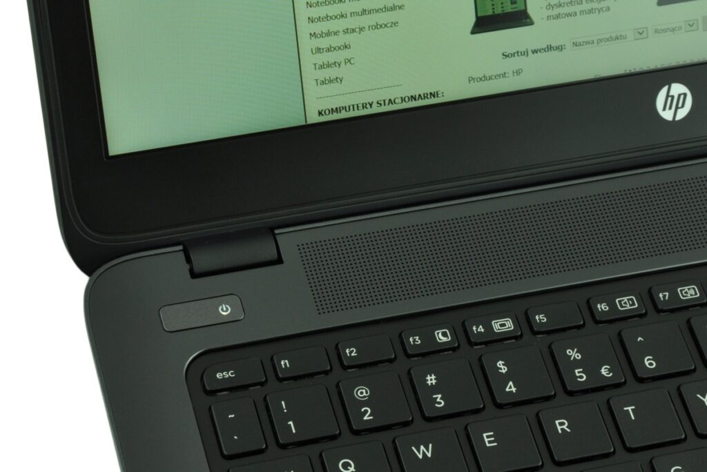 hp-zbook-14-g2-j8z75ea-c_130729 - lab-kuzniewski.pl - Testy laptopów, recenzje i porównania Close-up of a black HP laptop keyboard and hinge with a screen showing Polish text on a green-tinted page.