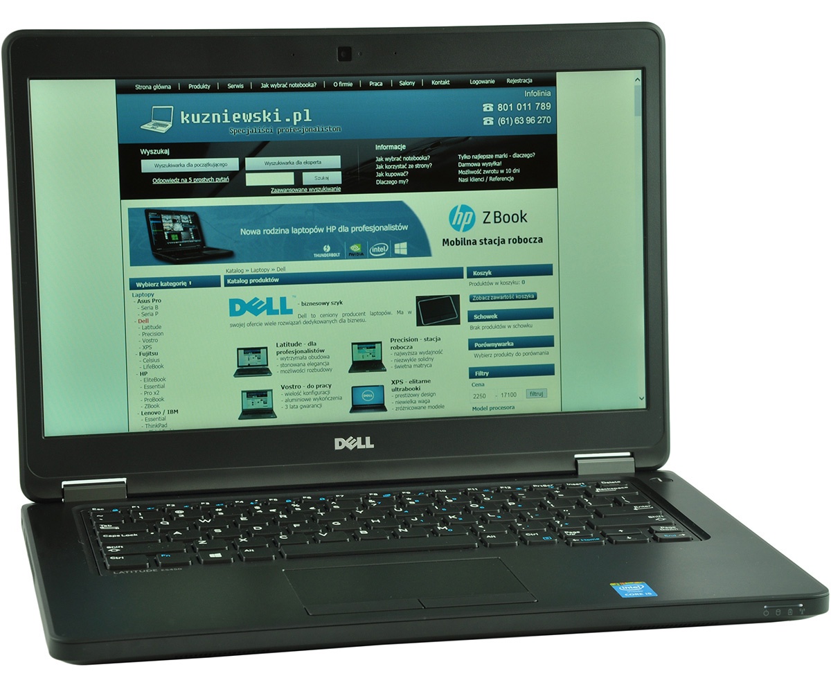 Dell laptop on a white surface displaying a Polish tech website kuzniowski.pl on the screen.