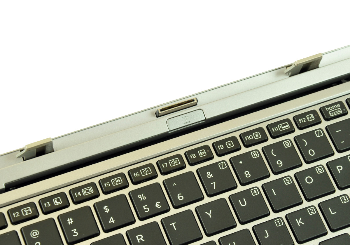 Close-up of a silver laptop keyboard showing the top edge with a docking/connector port and surrounding keys (F1–F12 area).