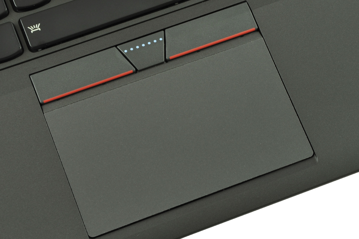 laptop-lenovo-thinkpad-t450s-6 - lab-kuzniewski.pl - Testy laptopów, recenzje i porównania Close-up of a dark laptop touchpad with red trim and a three-button bar above it, featuring a small dotted indicator area.