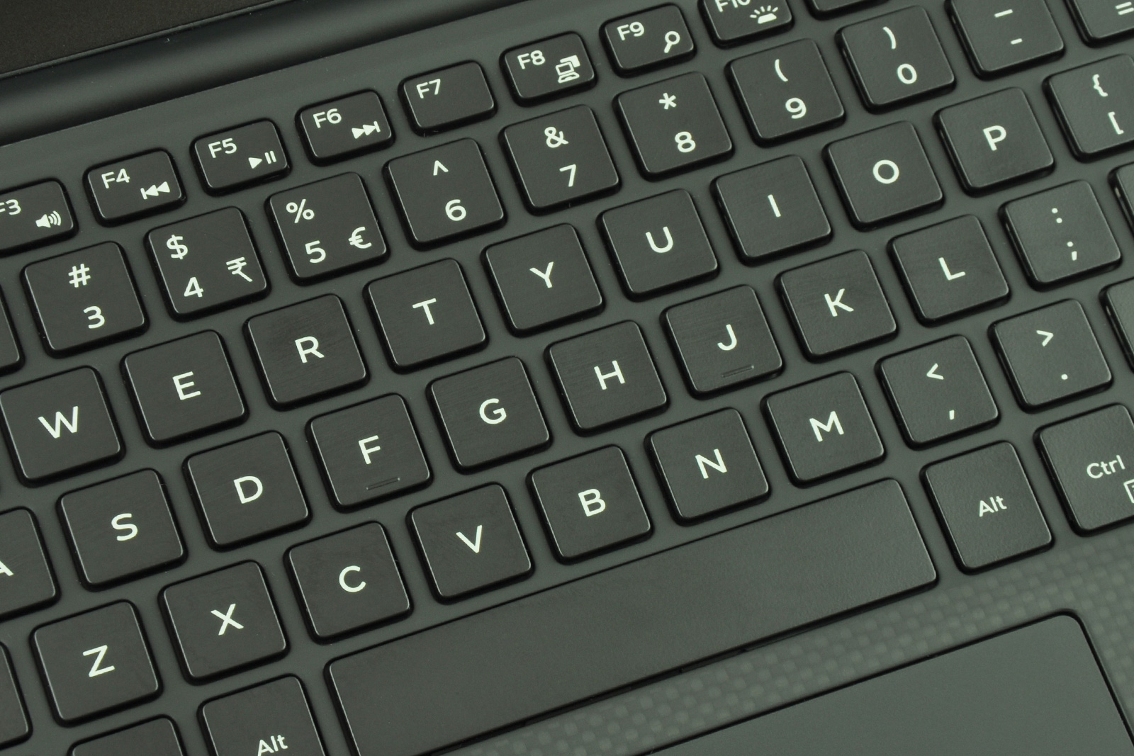 Close-up of a black laptop keyboard showing rows of square keys with white letters and symbols, including the Alt key at the bottom edge. placeholder for tactile keyboard texture.