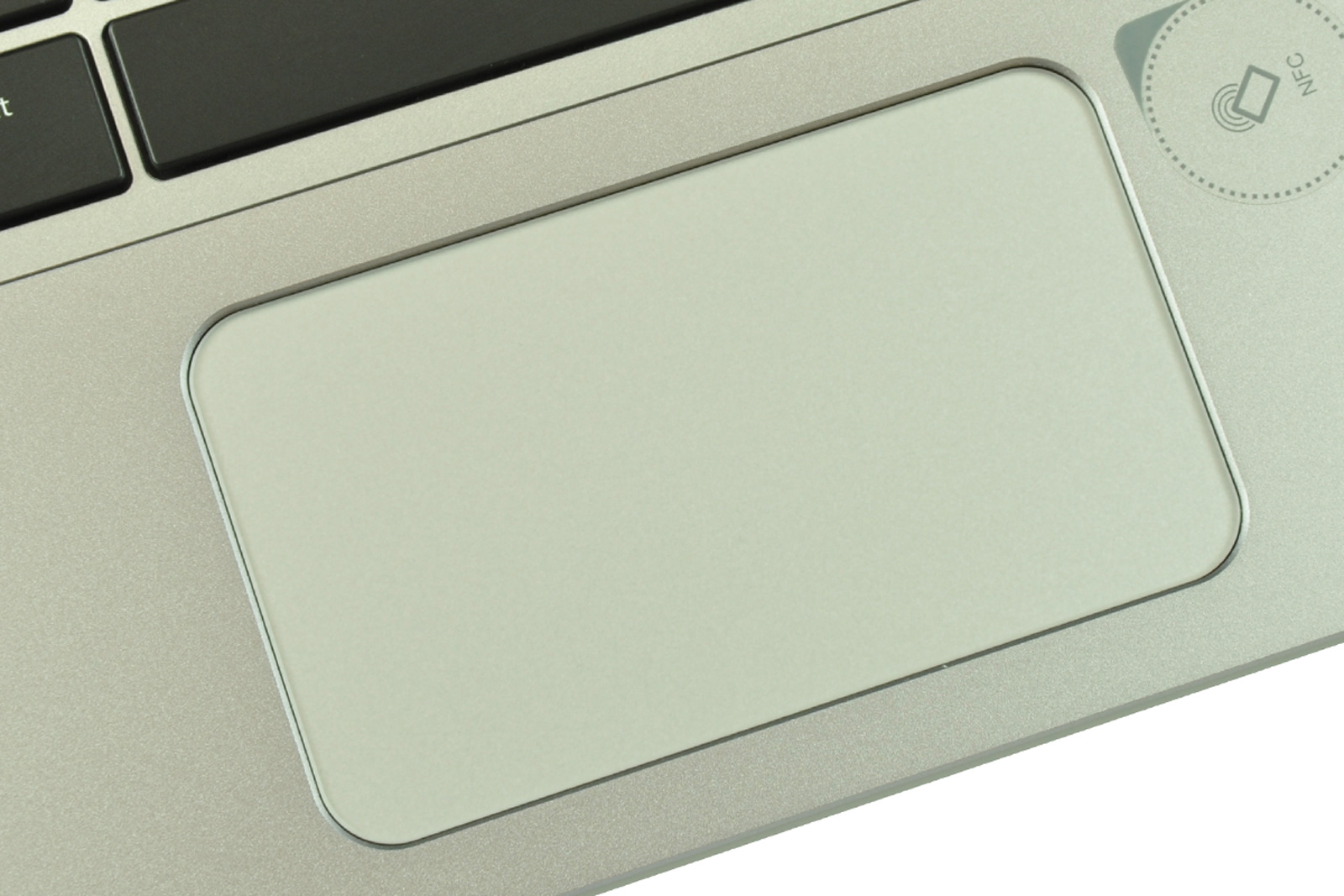 Close-up of a silver laptop touchpad with a partial keyboard and an NFC circle on the right.