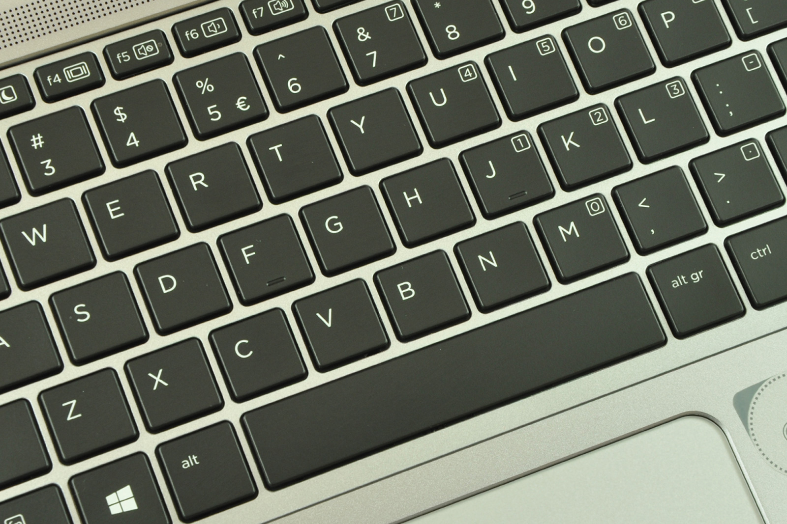 Close-up of a laptop keyboard showing dark gray keys with white letters and symbols on a silver chassis.