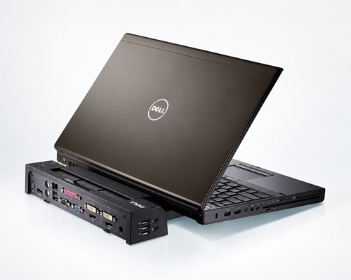 dell_latitude_e7270_2019_poradnik_lab - lab-kuzniewski.pl - Testy laptopów, recenzje i porównania Dell laptop docked on a black multi-port docking station with USB, video, and network ports on a white surface.