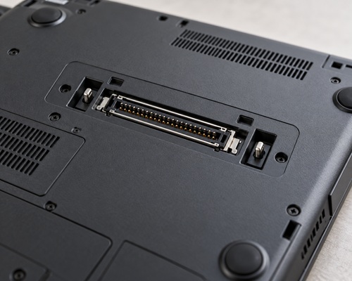 gniazdo_dokowania_2019_poradnik_lab - lab-kuzniewski.pl - Testy laptopów, recenzje i porównania Close-up of a laptop bottom showing a wide docking port surrounded by screws and vents.