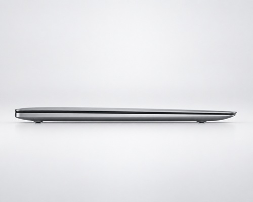 smukly_dell_xps_2019_poradnik_lab - lab-kuzniewski.pl - Testy laptopów, recenzje i porównania Slim silver laptop closed on a white surface, viewed from the side.