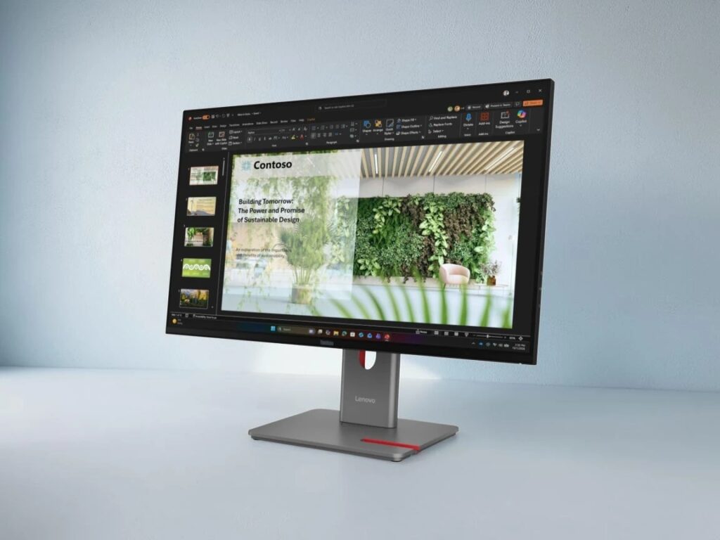 Lenovo ThinkVision P27UL-40_02 - lab-kuzniewski.pl - Testy laptopów, recenzje i porównania Lenovo monitor on a stand displaying a PowerPoint slide about sustainable design with a green wall image in the presentation.