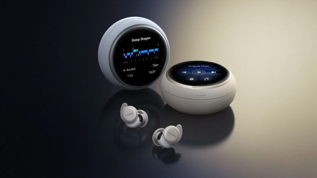 Soundcore Sleep Earbuds 4 Pro_00 - lab-kuzniewski.pl - Testy laptopów, recenzje i porównania Two round white charging cases and two white Anker earbuds sit on a dark, reflective surface, with a screen showing sleep stages nearby as a product shot of sleep earbuds.
