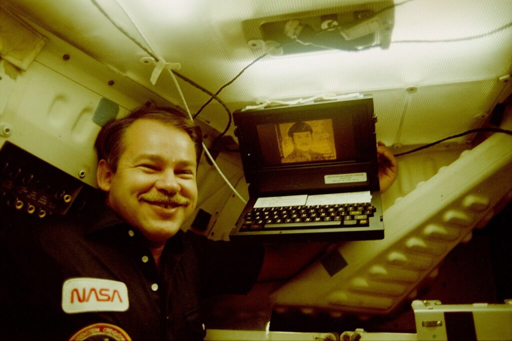 10_co_to_jest_ultrabook_poradnik_LAB_3010_GRiDCompassInSpace_ze_SPOCKiem - lab-kuzniewski.pl - Testy laptopów, recenzje i porównania NASA crew member in a capsule, smiling with a laptop floating in zero gravity.