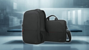 Lenovo_4X41C12468_und_4X41C12469_001 2 - lab-kuzniewski.pl - Testy laptopów, recenzje i porównania Two black backpacks in a sleek blue-toned office setting, one larger with a red zipper pull in front of a glass backdrop.